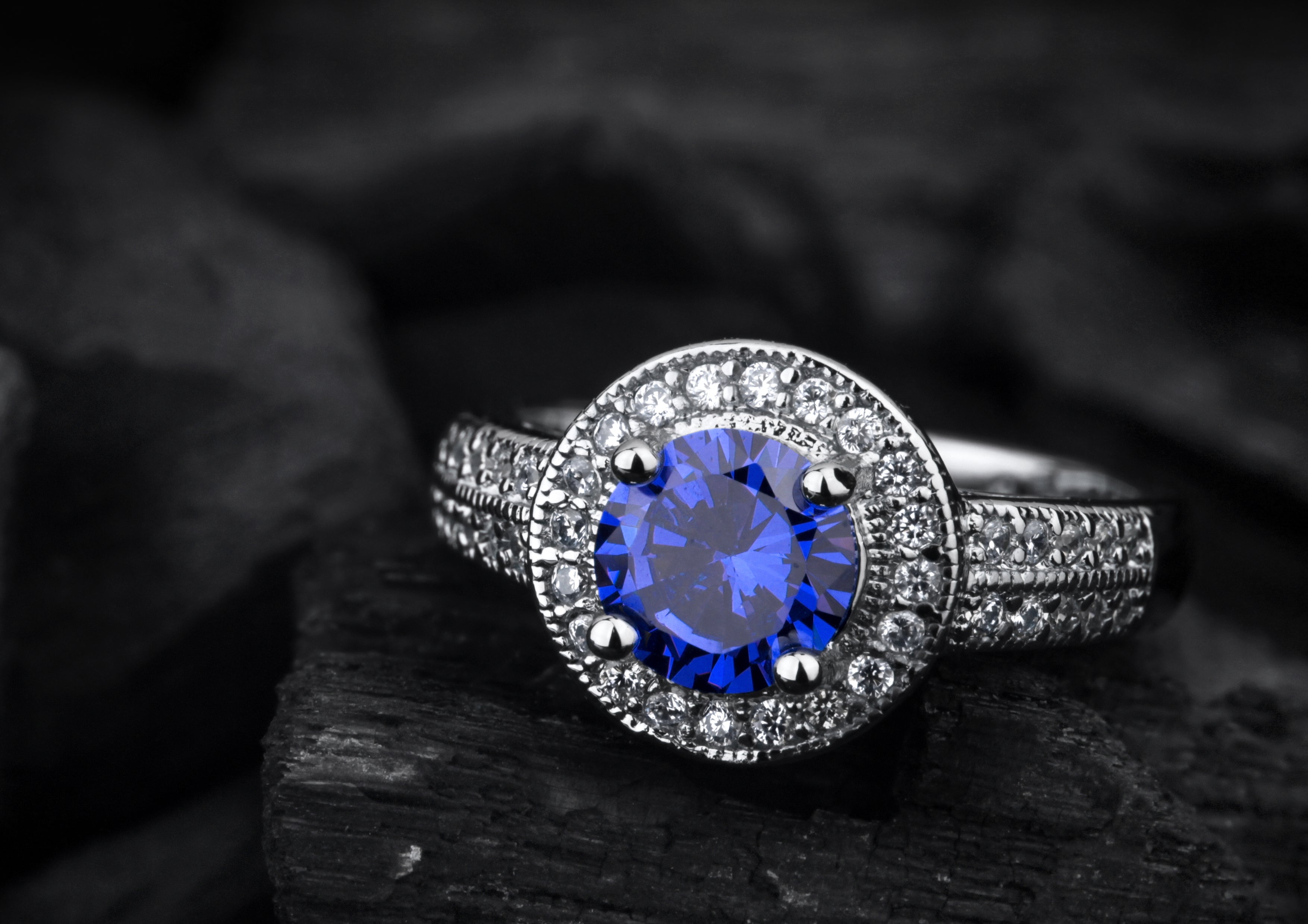 Jewellery ring with big blue sapphire on black coal background