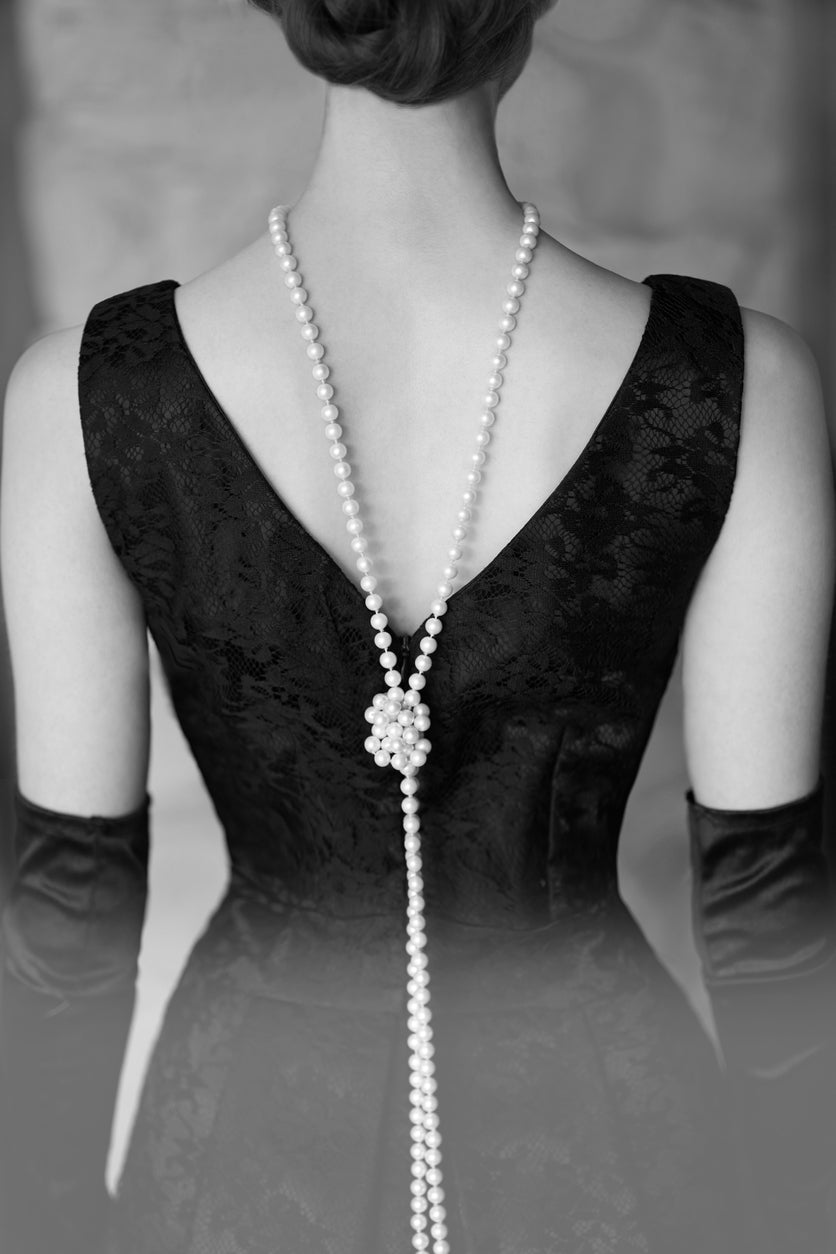 Beautiful woman figure  in a black dress and pearls in the style of 20-30 years of the XX century. Vertical portrait with copy space. Book cover design.