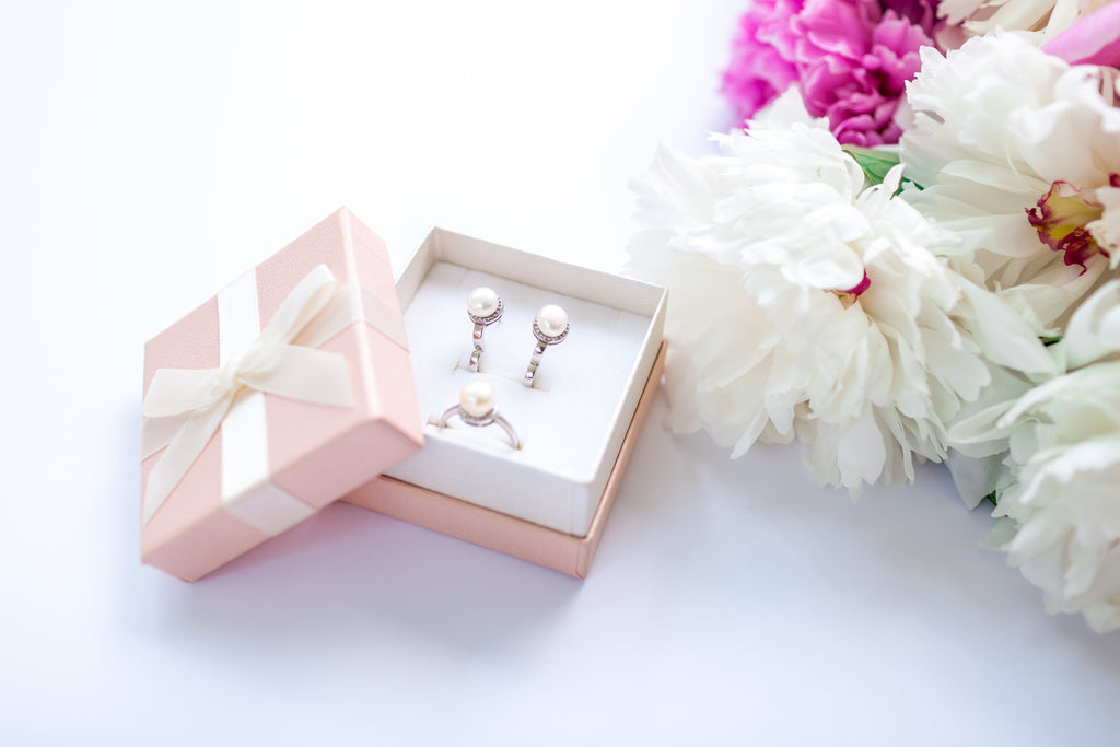 Set of silver ring and earrings with pearls in the gift box with bouquet of peonies. Present for holiday