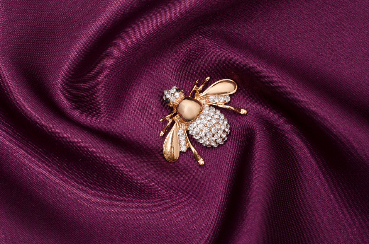 Golden brooch bee with diamonds on silk fabric